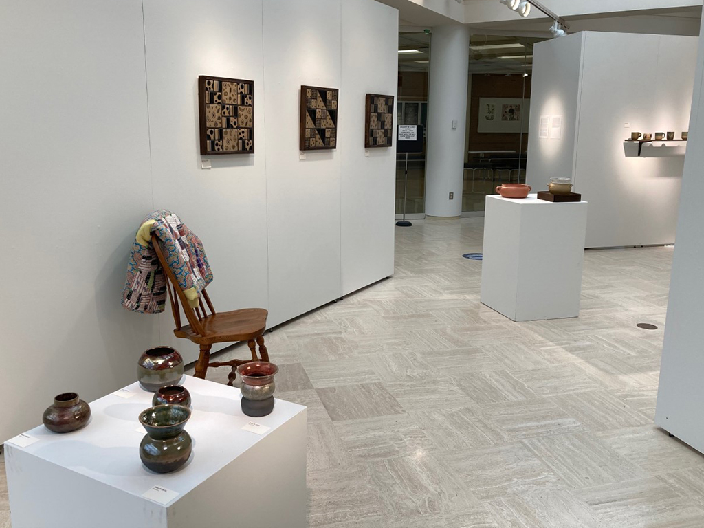 raku vessels and tile quilts with quilt over a chair looking toward front entrance